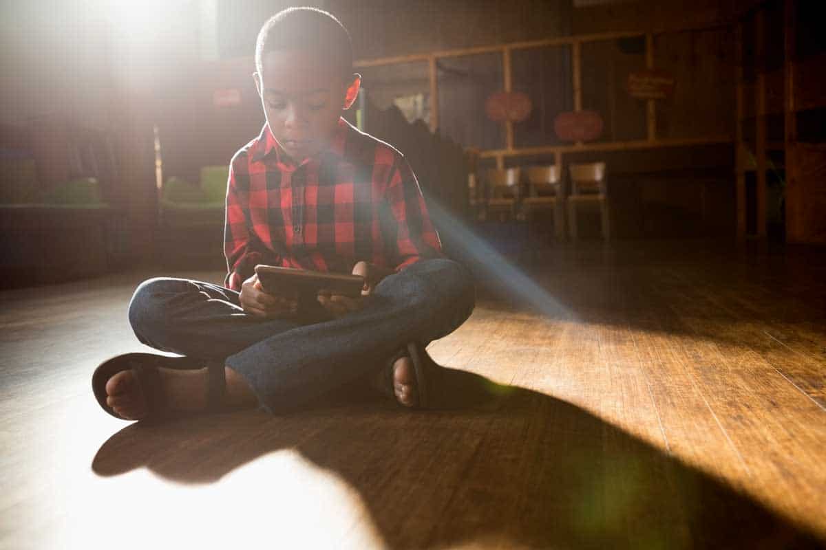 Boy Sitting On Wooden Floor In The Sun