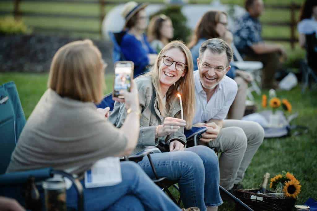 Group of diverse adults enjoying an outdoor community event, smiling and engaging with each other on a sunny day.
