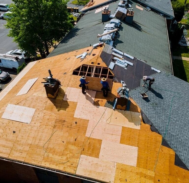 Roofers working on a large residential building roof