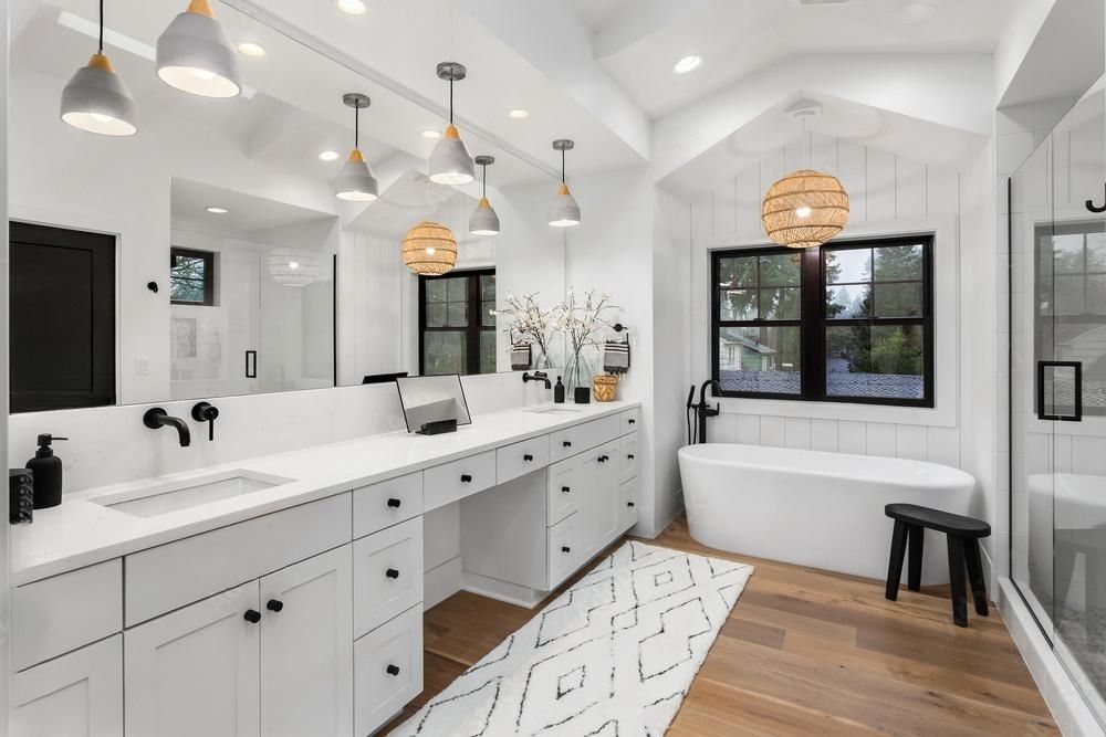 Modern white bathroom with double vanity, large mirror, and freestanding tub.