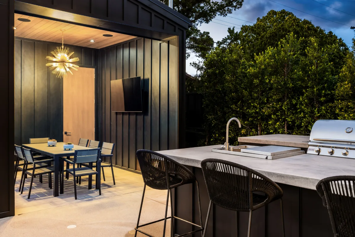 Outdoor kitchen and dining area with modern design and lush greenery