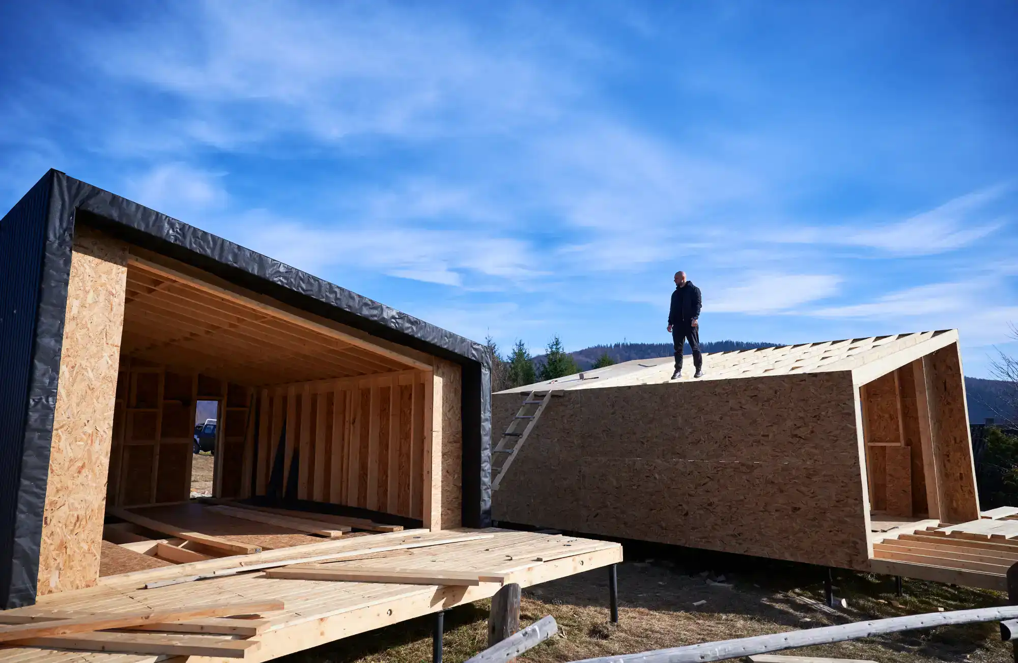 Man standing on a wooden roof of a house under construction
