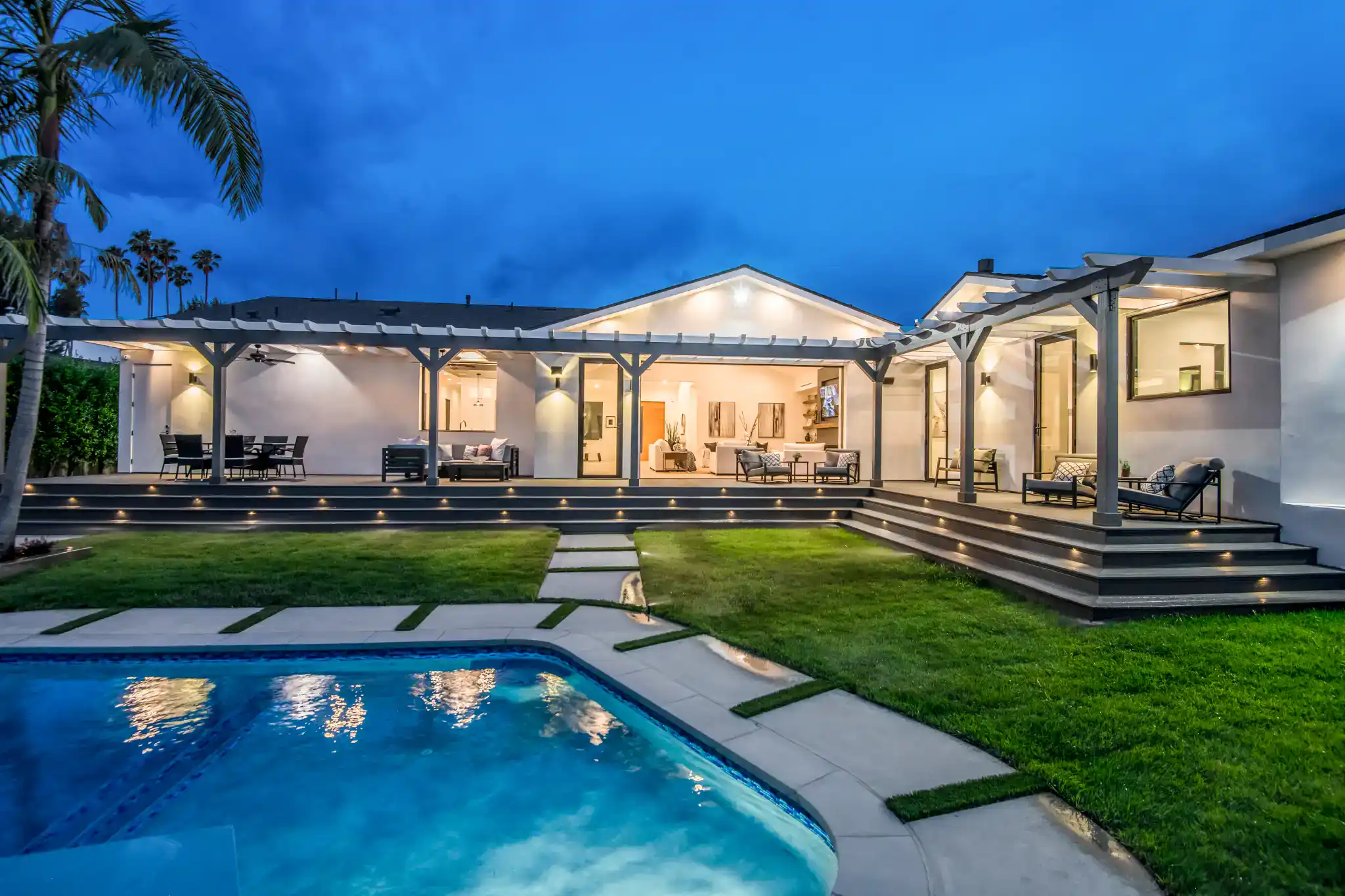 Modern house with pool, patio, and outdoor seating at dusk.