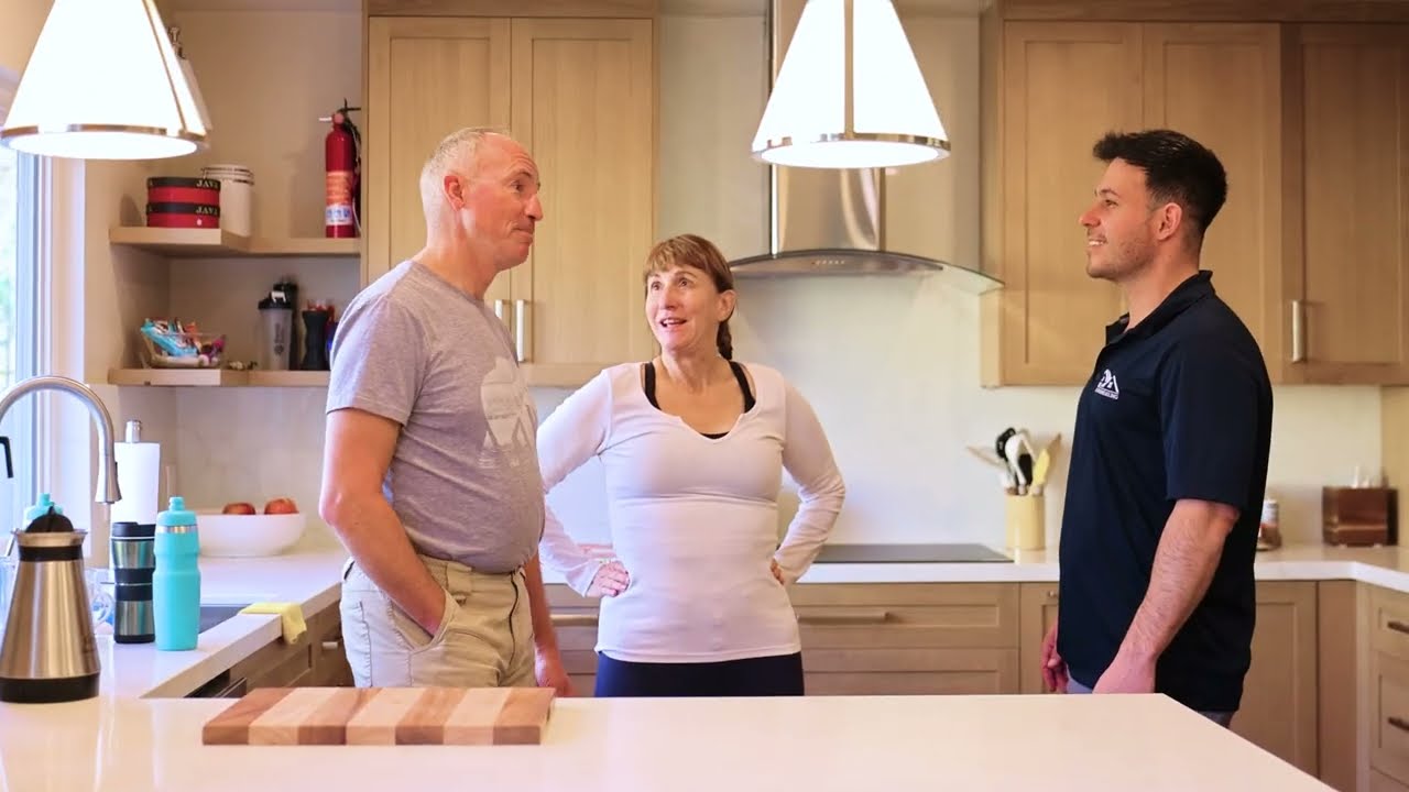 Two adults talking to a man in a kitchen.