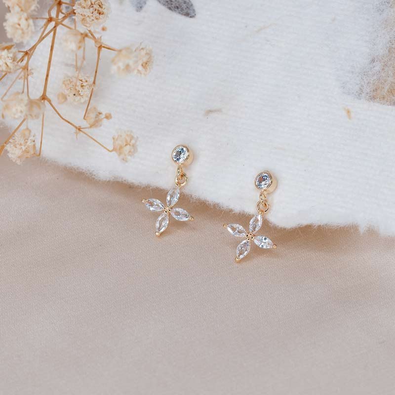 Dainty floral stud earrings in warm gold on a neutral backdrop