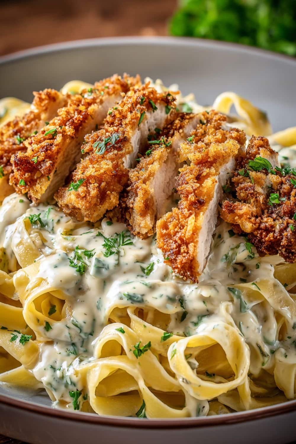 Crispy panko-breaded chicken sliced over creamy fettuccine Alfredo sauce garnished with parsley