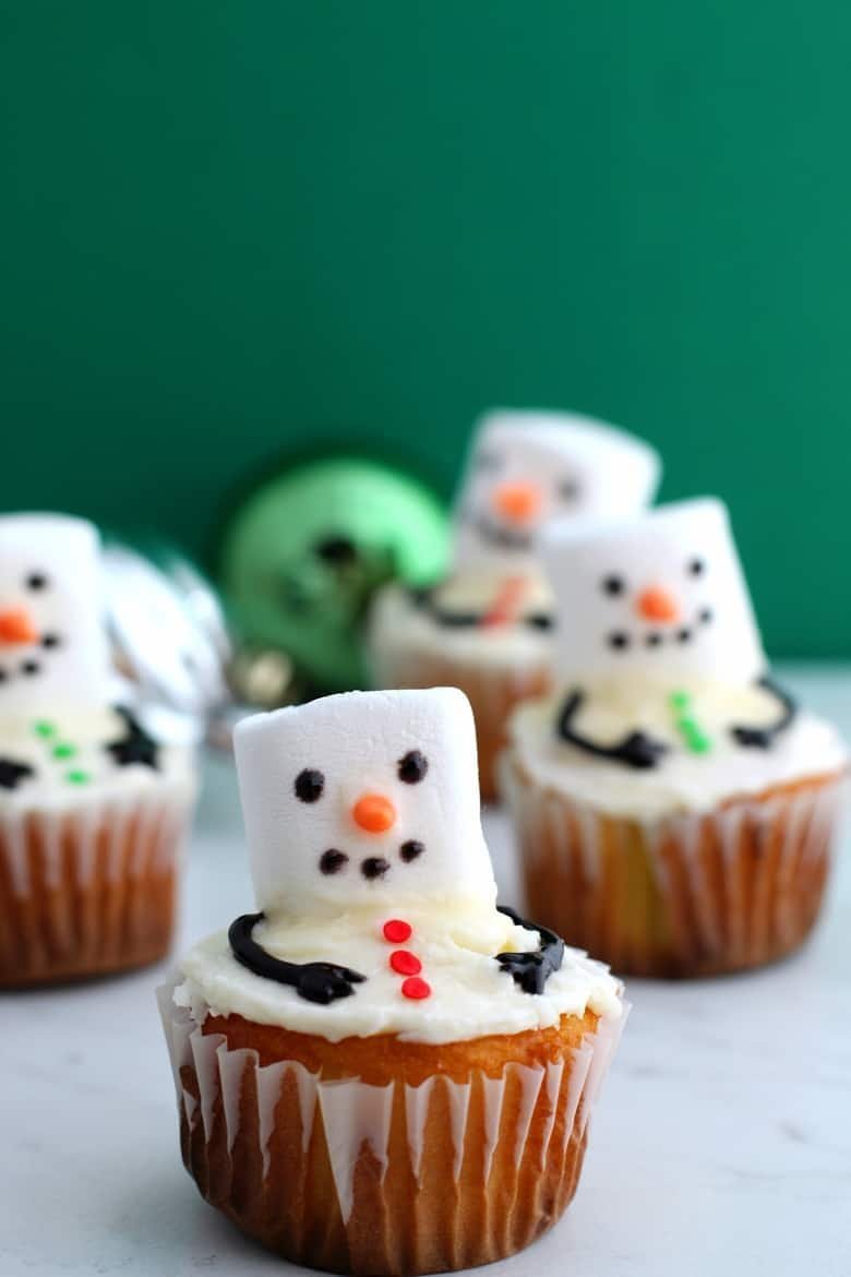 Melted snowman cupcakes with marshmallow heads and winter decorations