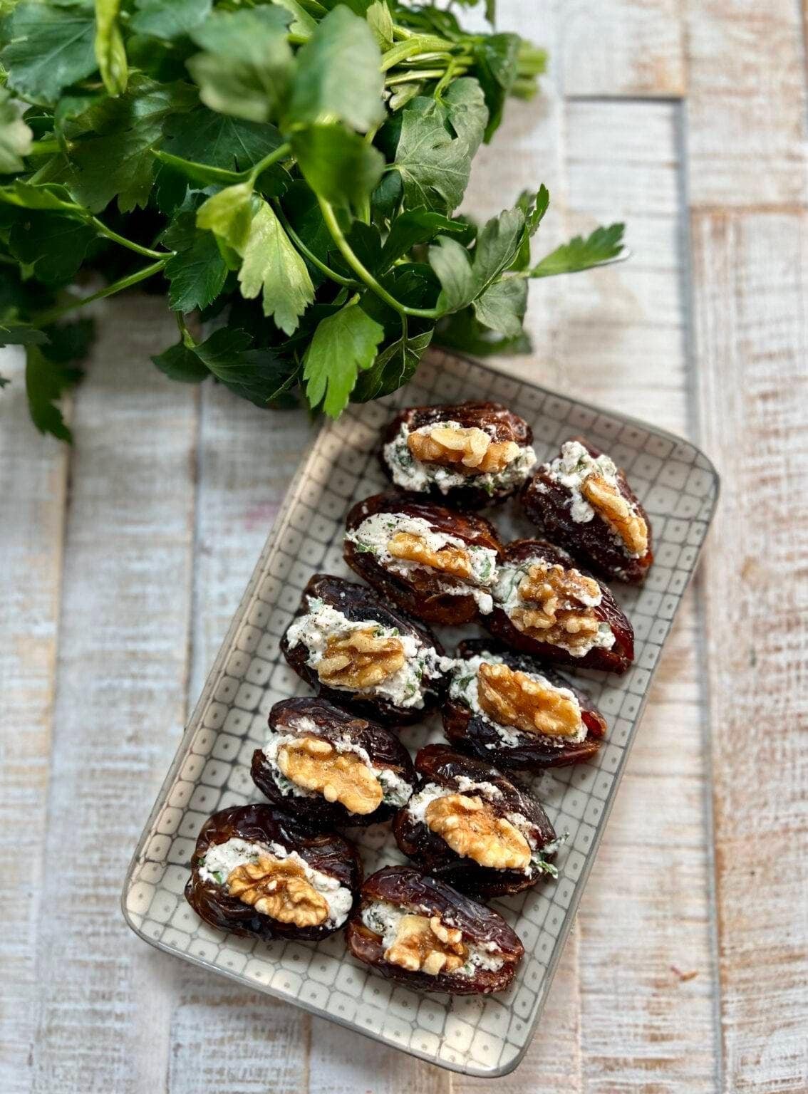Vegan stuffed dates topped with nuts and herbs.