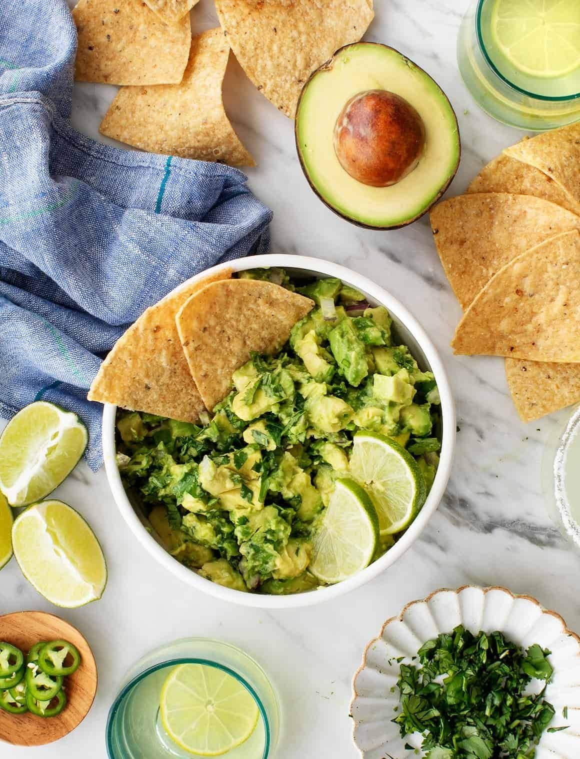 Fresh guacamole in a bowl served with tortilla chips and lime.
