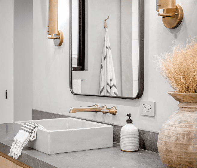 A bathroom with a sink, mirror and a vase.