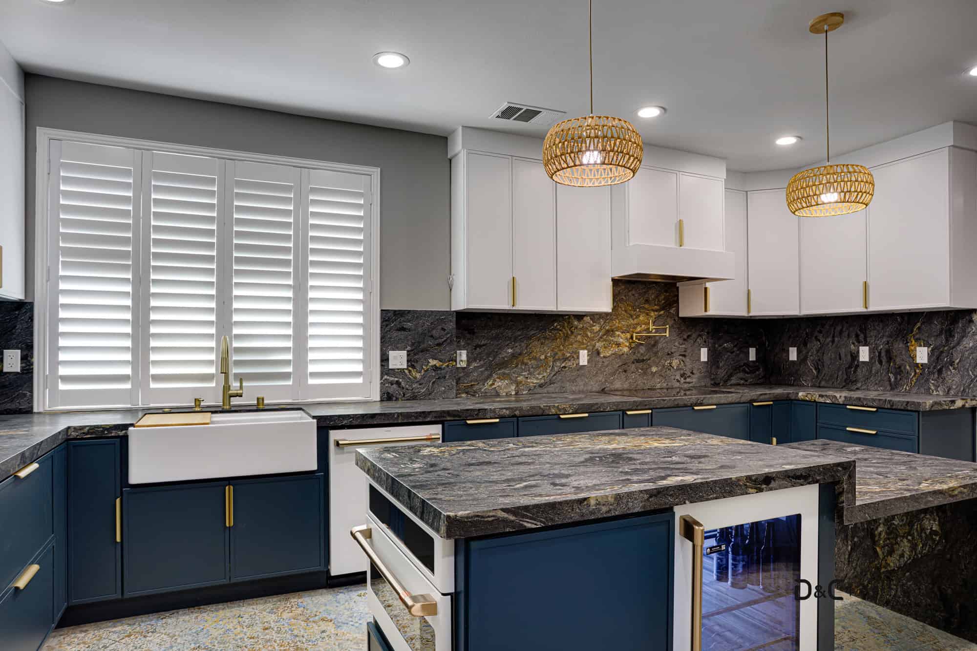 Sleek kitchen remodel with brushed gold accents, slab backsplash, and matte navy blue drawers
