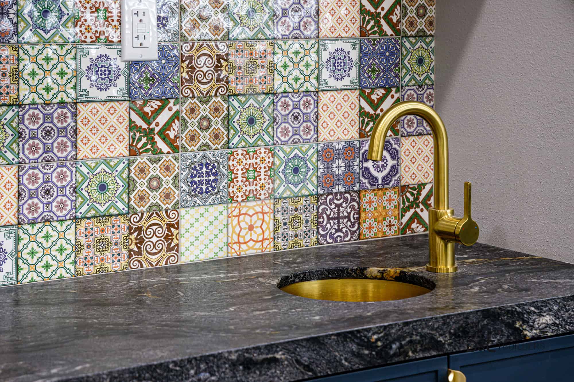 Luxury wet bar with navy blue cabinets, round gold sink, and eclectic tiled backsplash