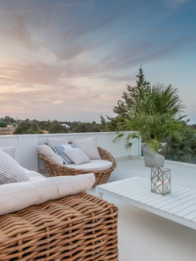 Terrace with wicker seating and Mediterranean views at sunset in Ibiza