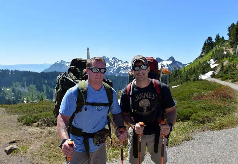 Two hikers walking on mountain trail with backpacks in scenic landscape