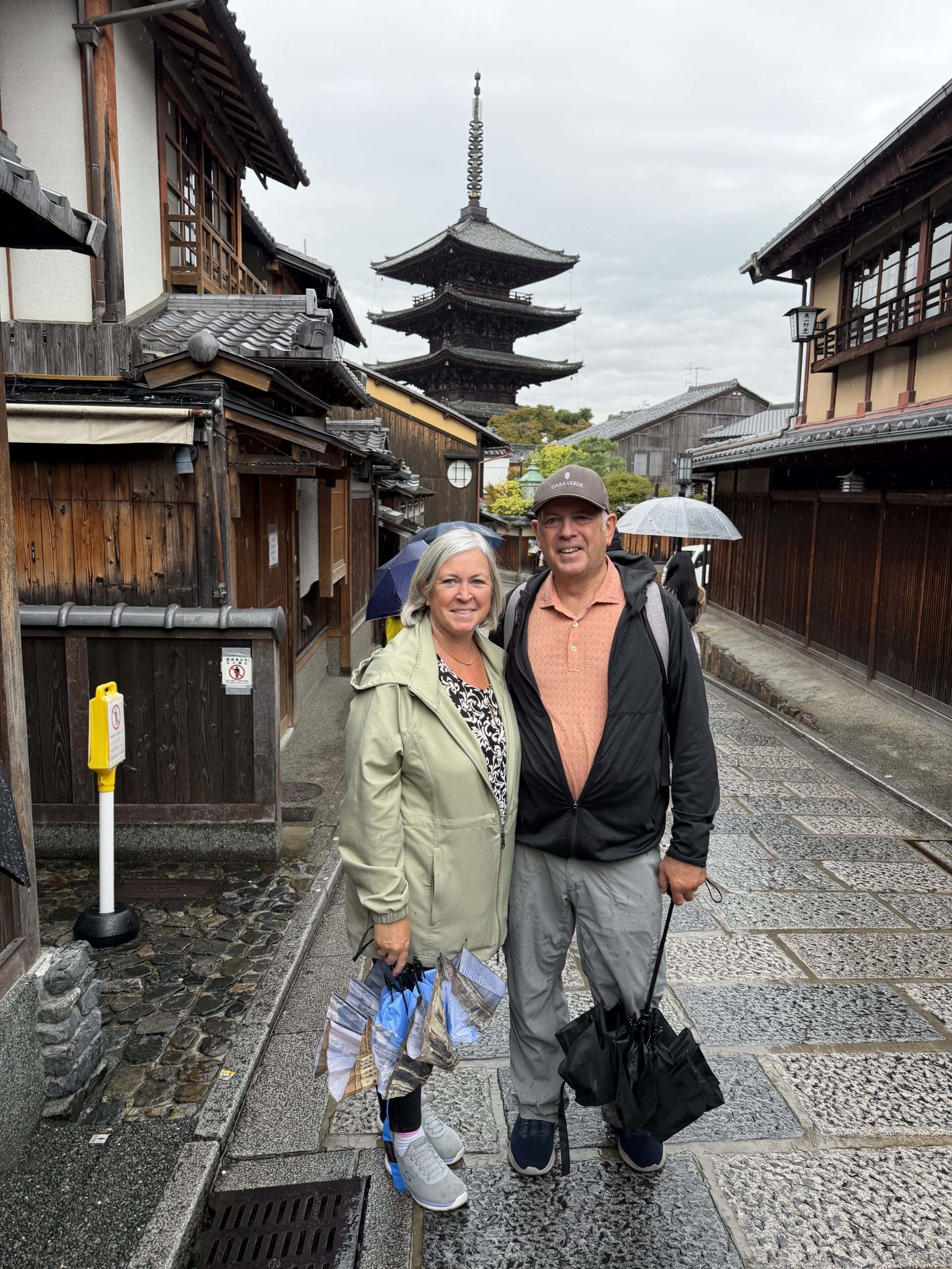 Traditional Japanese street scene with tourists under umbrellas.