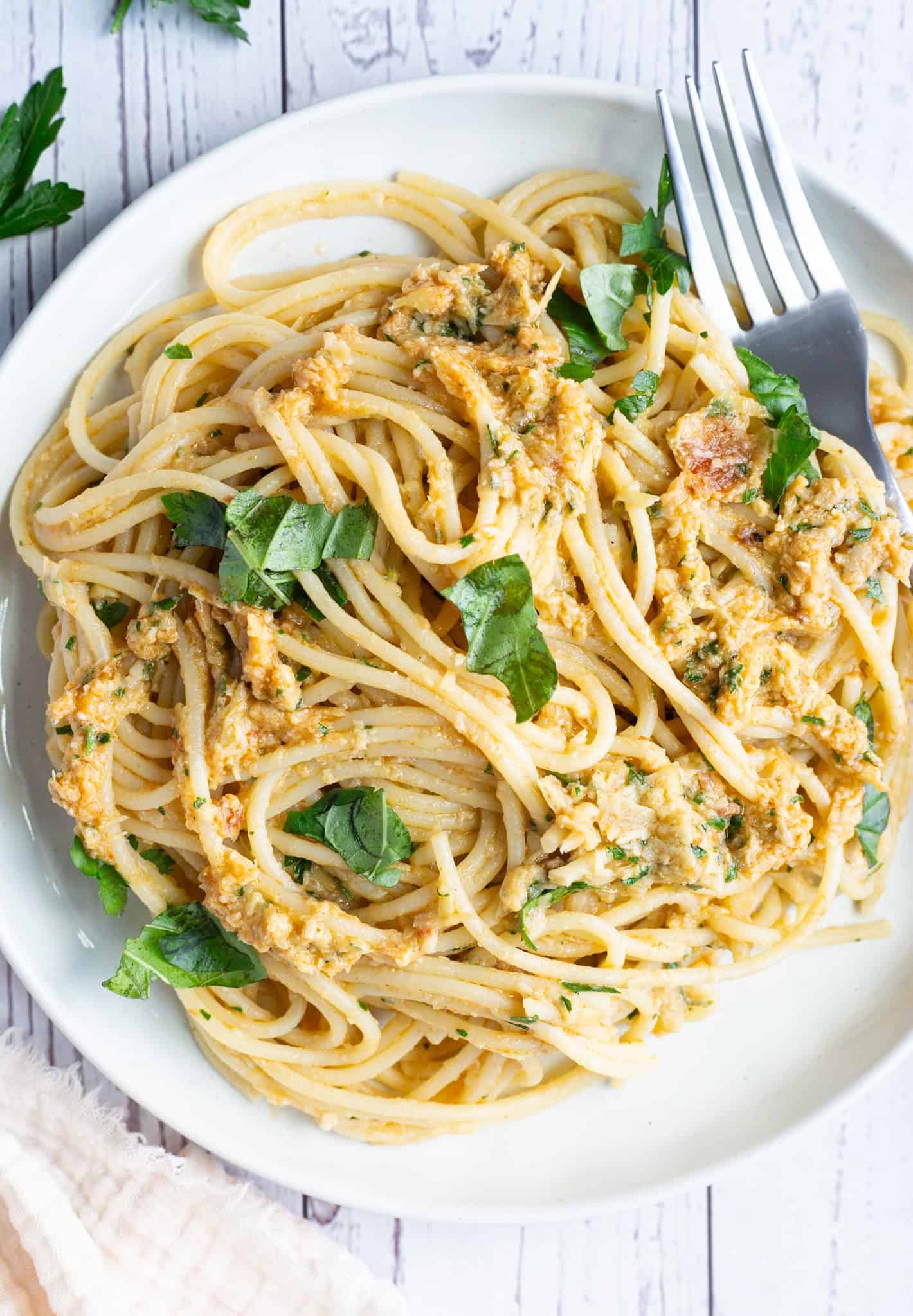 A plate of artichoke and sun-dried tomato pasta garnished with fresh basil.
