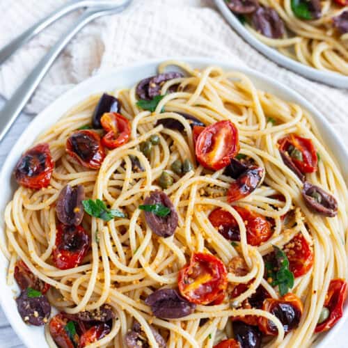 Two plates of linguine tossed with roasted tomato puttanesca.