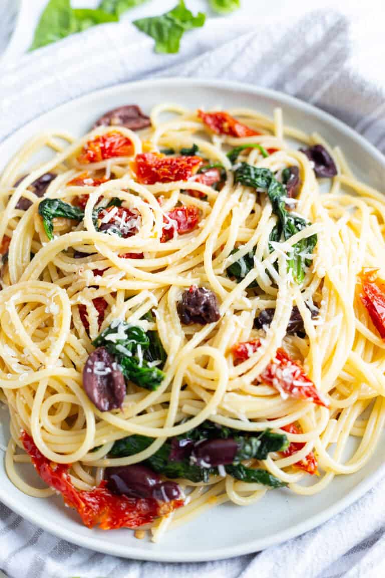 A plate of spaghetti made with Kalamata olives, sun-dried tomatoes, and baby spinach.
