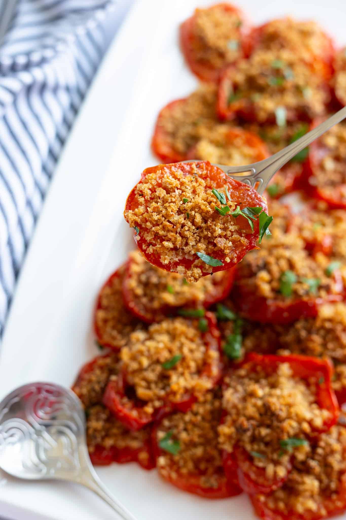 A closeup of a roasted vine tomato with seasoned breadcrumbs.