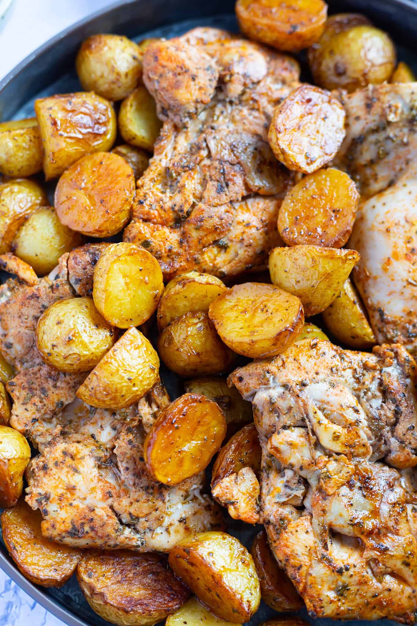 Baked vinegar chicken thighs with golden potatoes.
