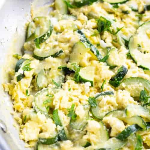A pan of scrambled eggs and zucchini.