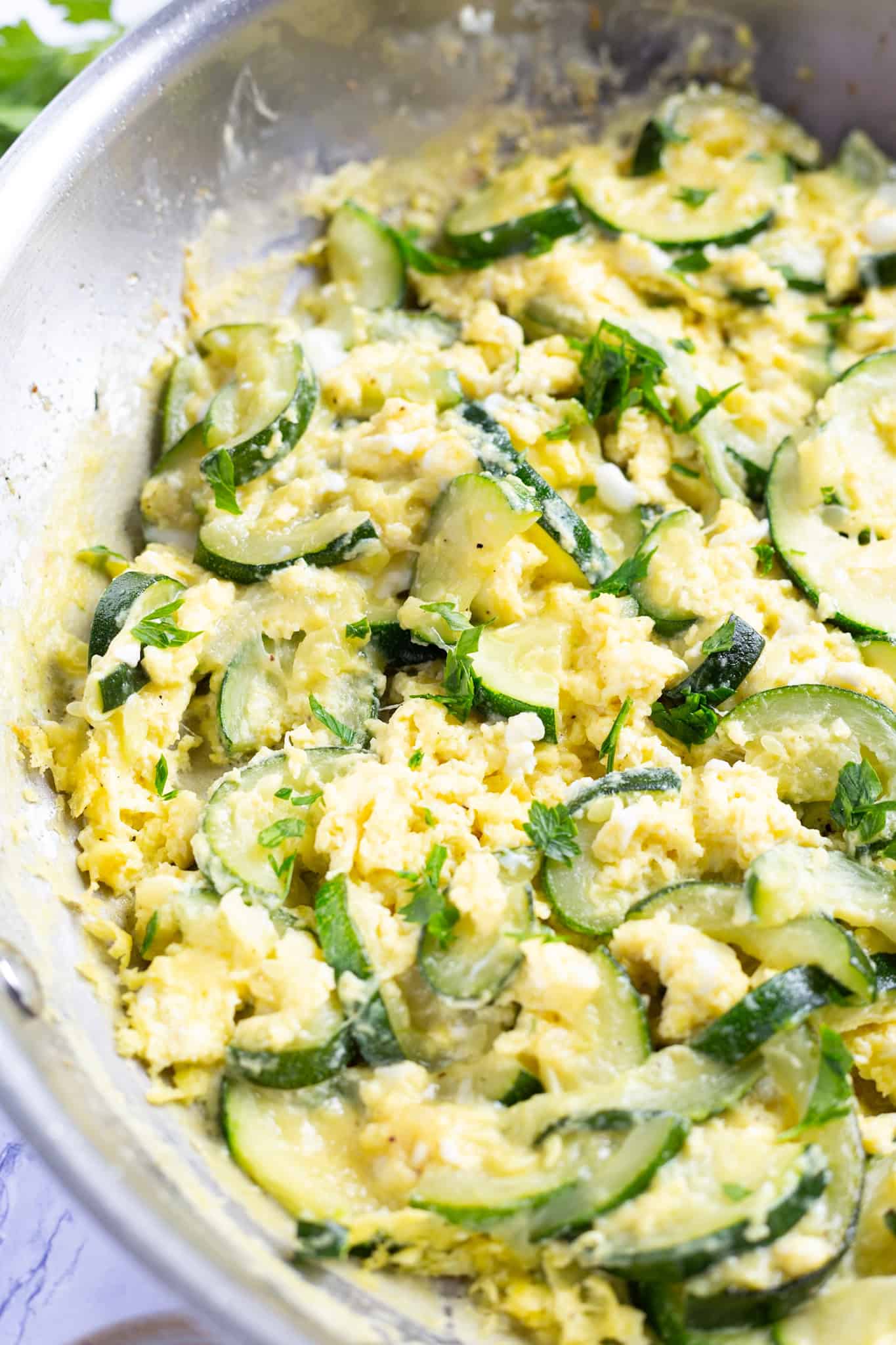 A pan of scrambled eggs and zucchini.