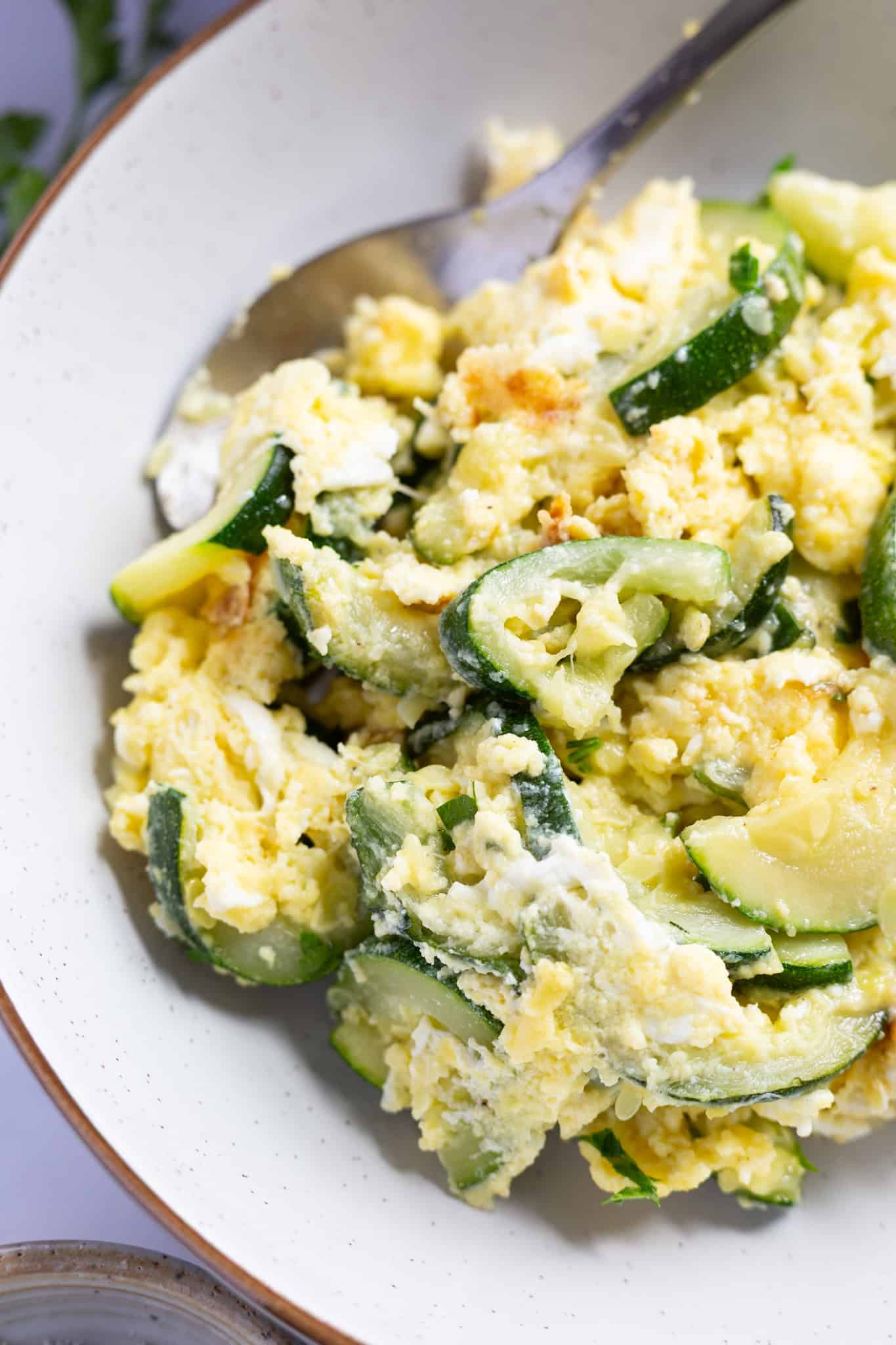A bowl of scrambled eggs and zucchini.
