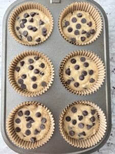 Filled muffin cups with chocolate chips added to tops.