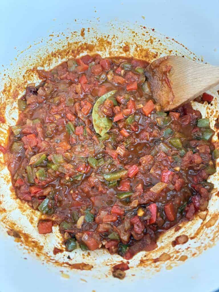 A pot of cooked diced tomatoes with veggies and spices for turkey chili.
