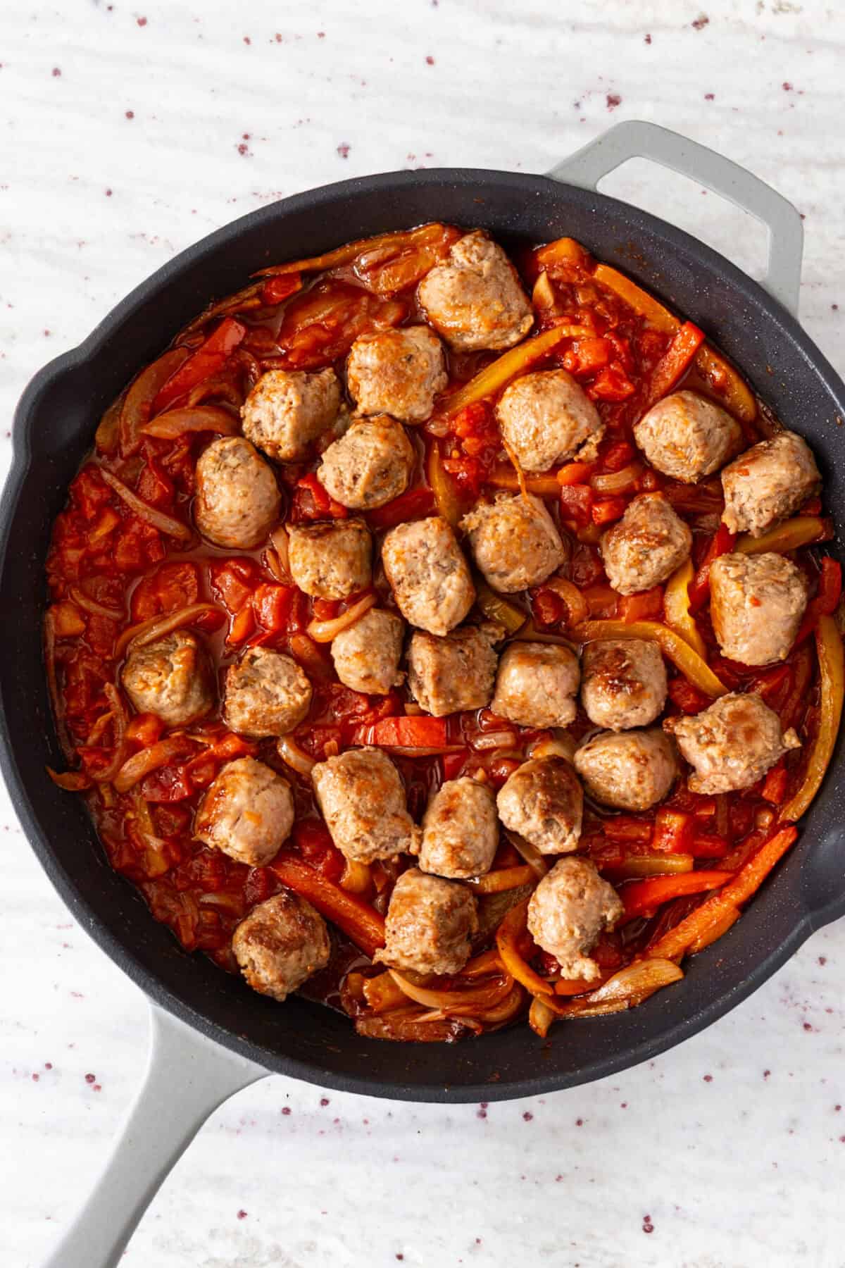 A pan of sausage, peppers, and tomatoes.