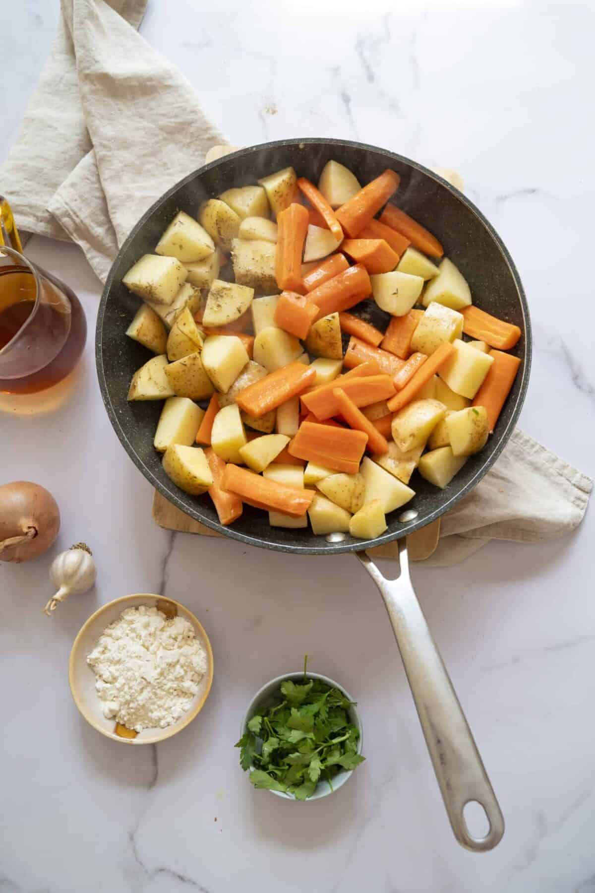 A pan of cooked potatoes and carrots.
