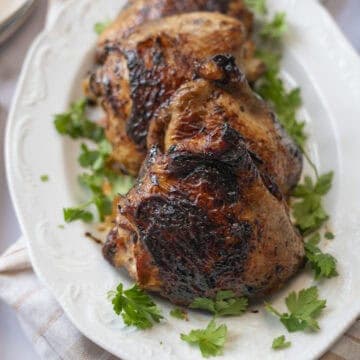 Juicy grilled bone-in chicken thighs framed by parsley sprigs.