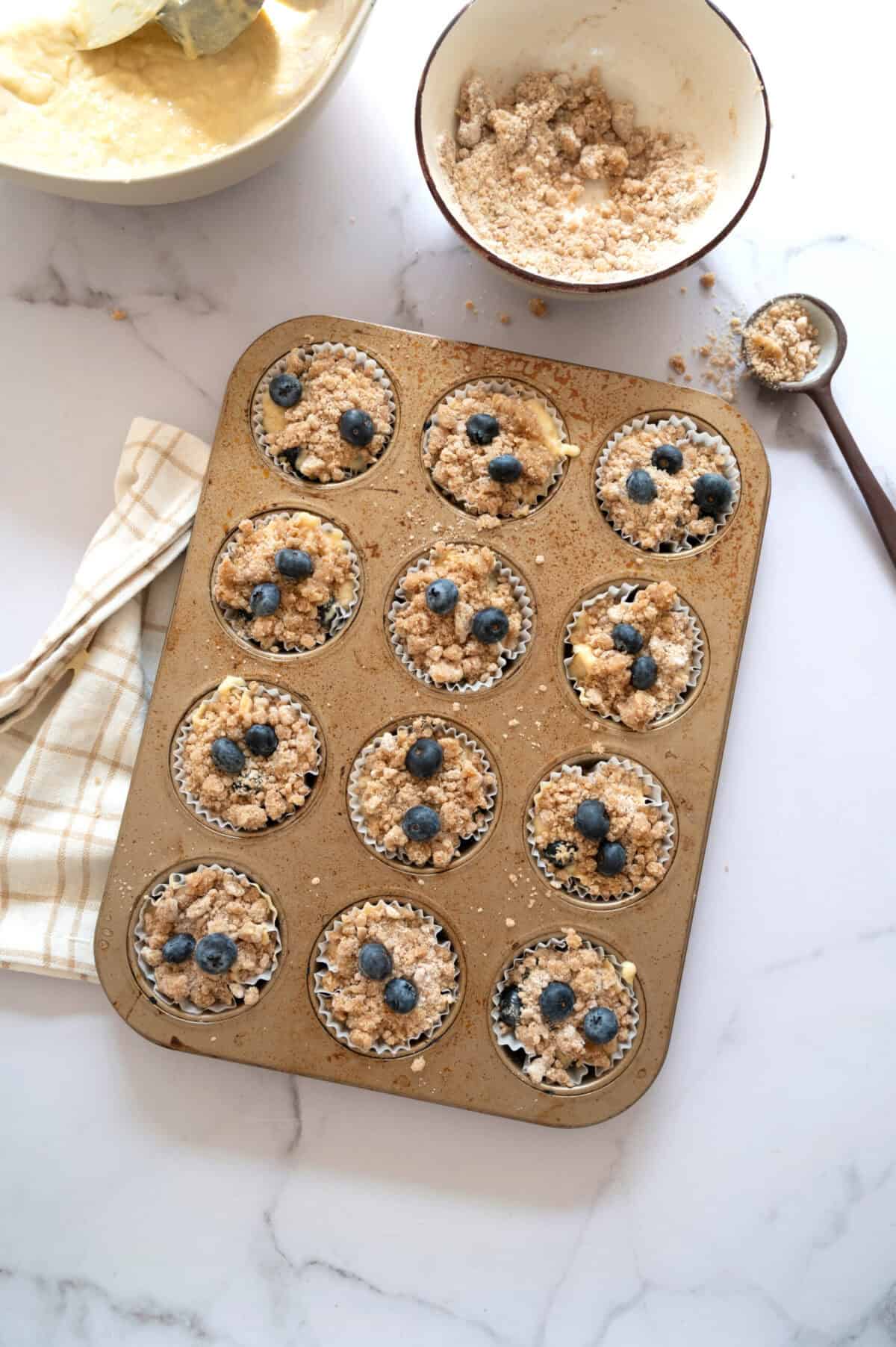 Muffin batter topped with streusel and blueberries.
