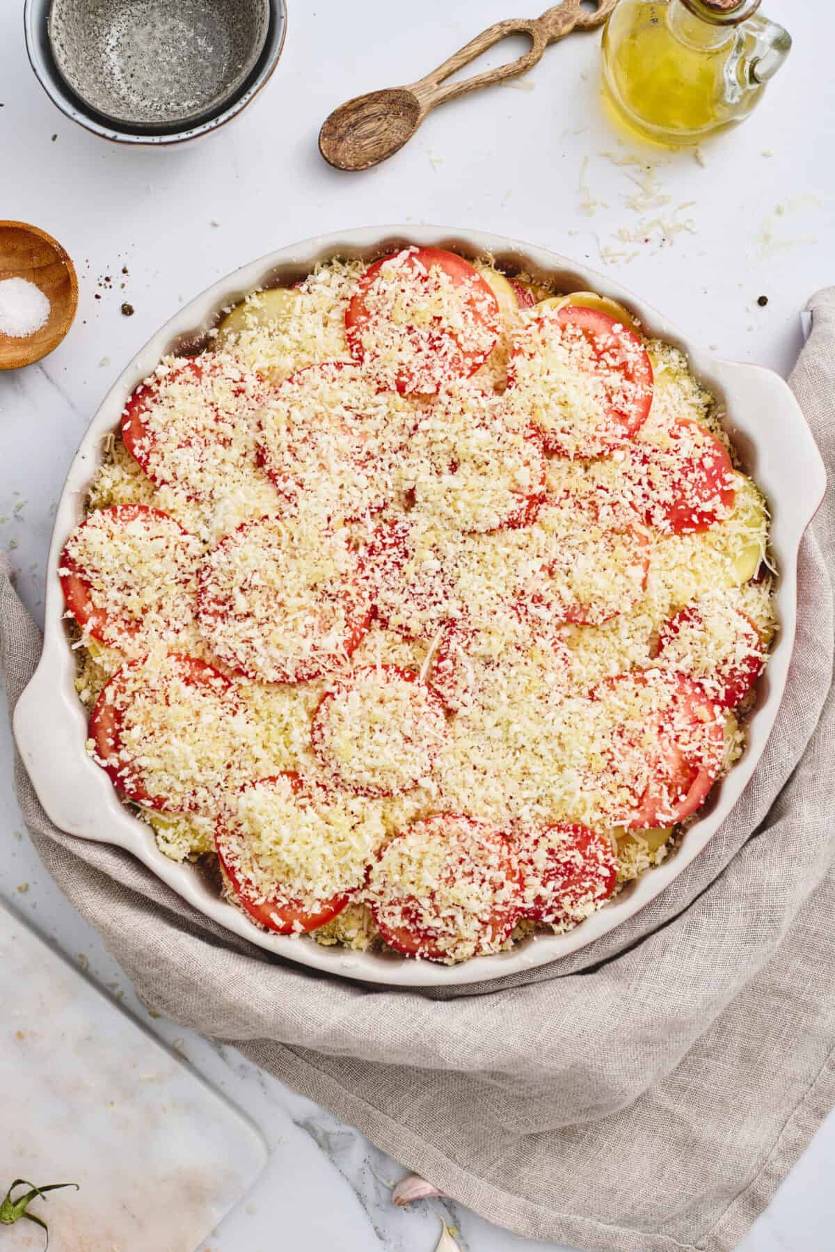 A dish of layered potatoes and tomatoes topped with panko.