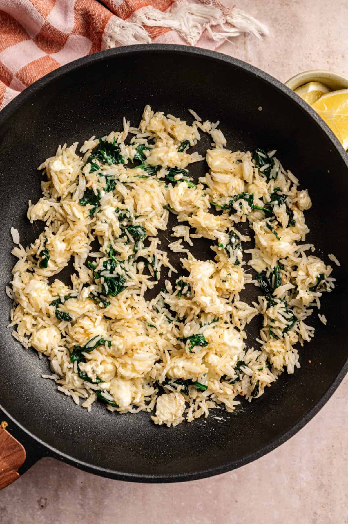 A pan of cooked rice, spinach, and feta.