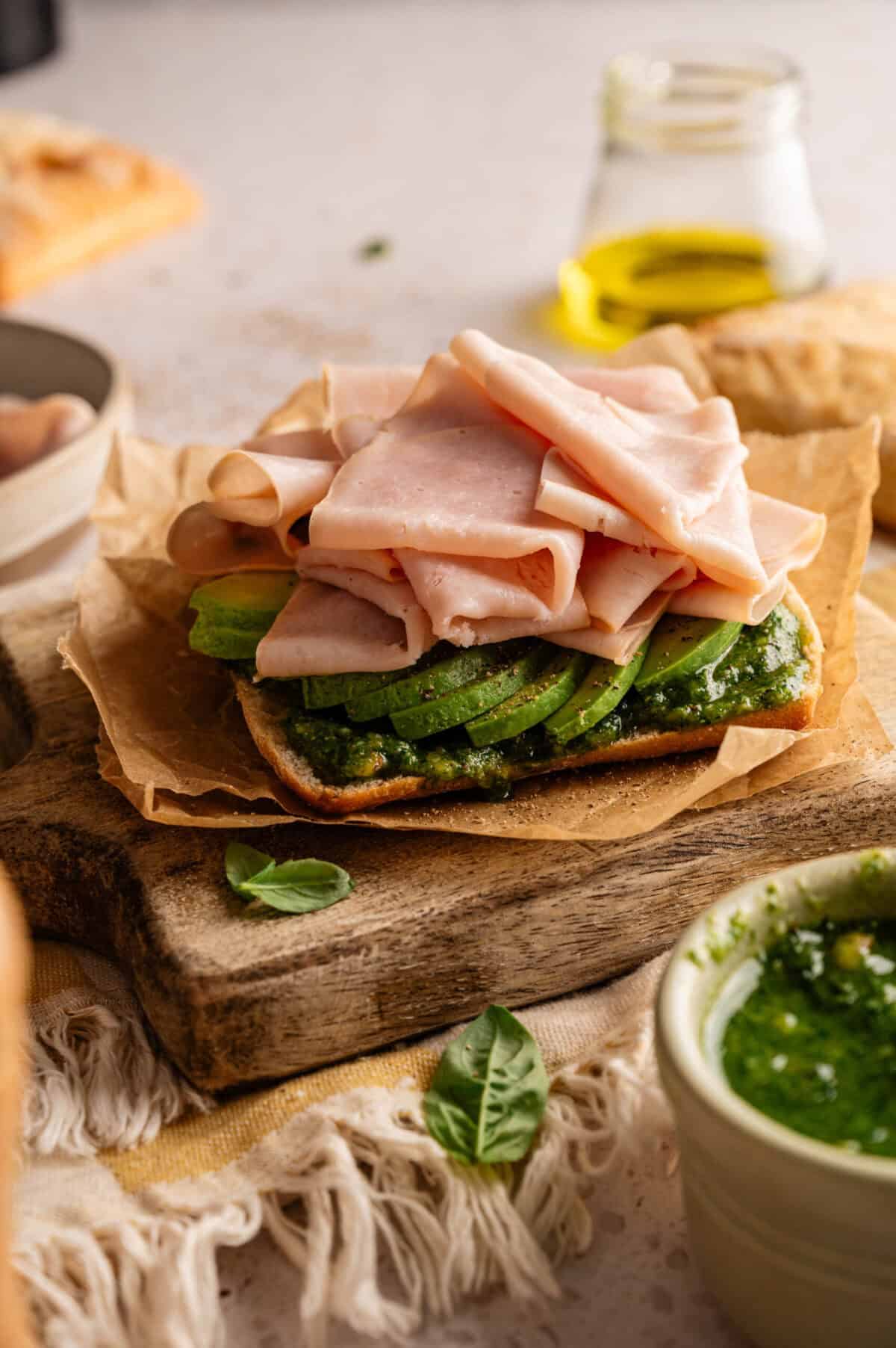 A sandwich stacked with pesto, avocado, and turkey.