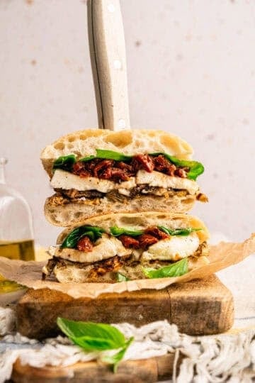 A stacked roasted eggplant sandwich with eggplant, mozzarella, sun-dried tomatoes, and fresh basil.
