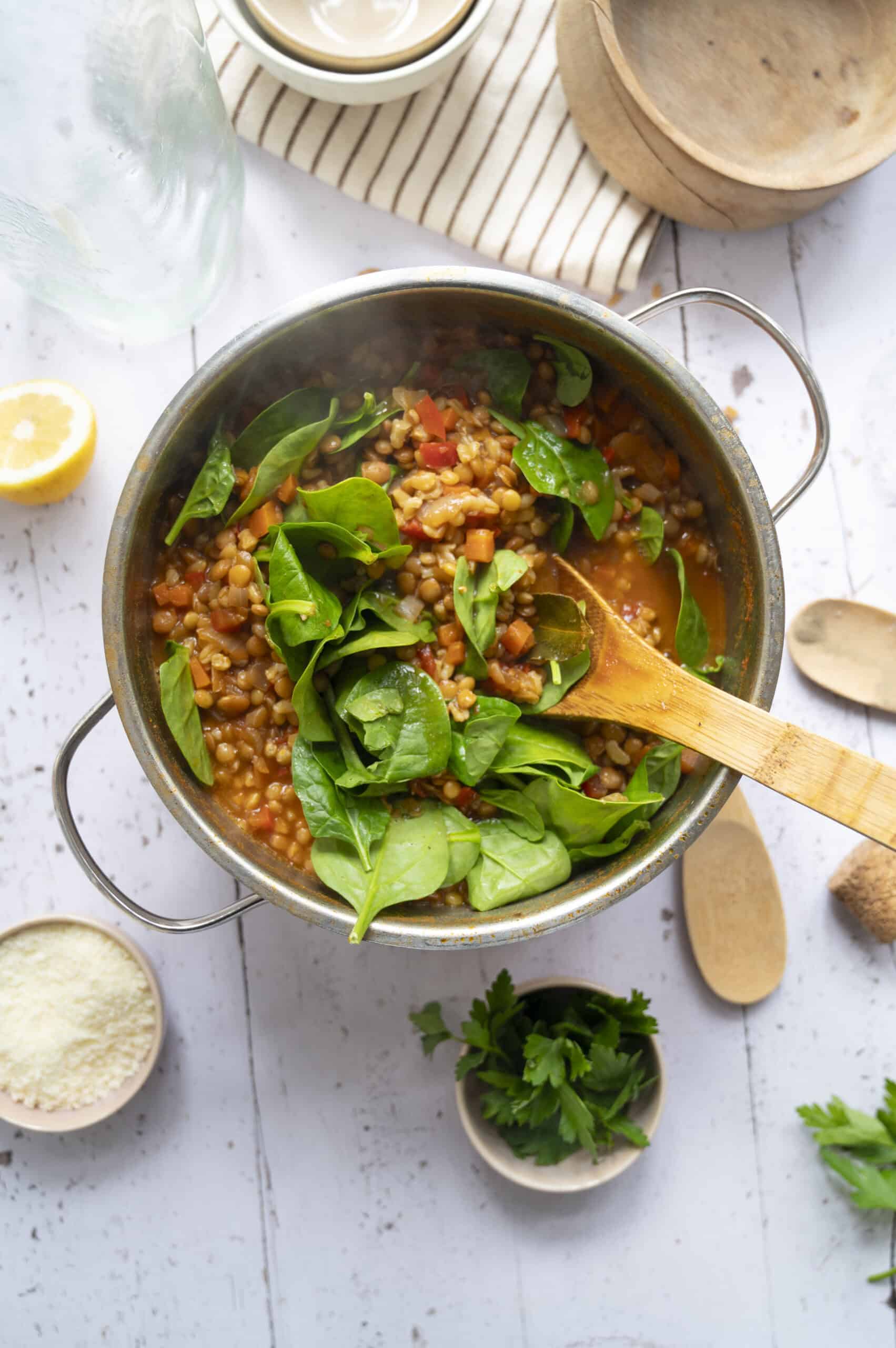 A pot of lentil and barley soup with spinach added.