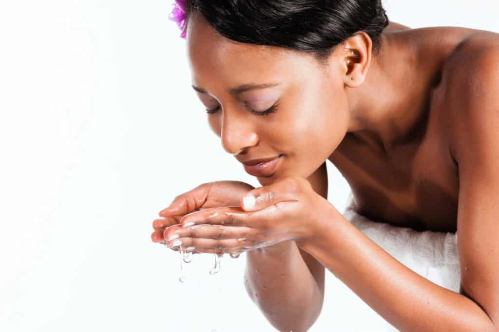 Woman applying skincare product, focusing on face and hands.