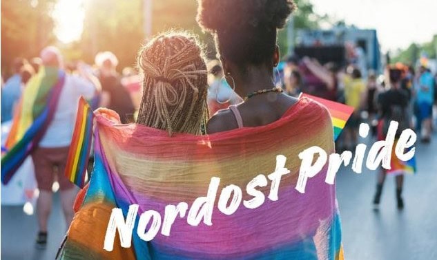 två personer insvepta i regnbågsflagga med texten Nordost pride