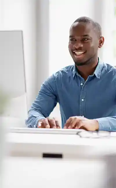Man smiling while typing at desktop computer