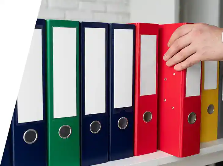 Hand pulling red binder from colorful shelf