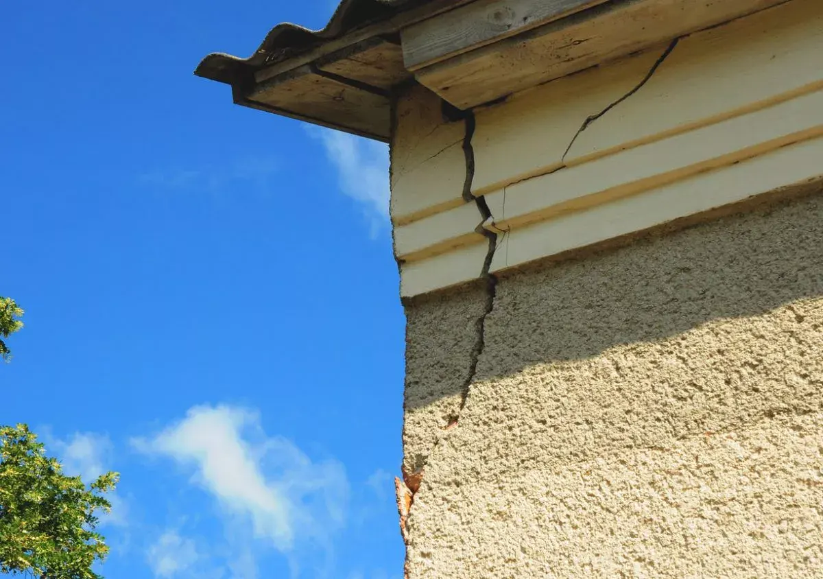 Large crack visible on the corner of a building under a blue sky
