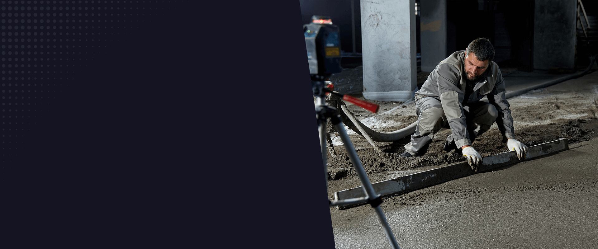 Man in grey work clothes leveling fresh concrete with a tool.