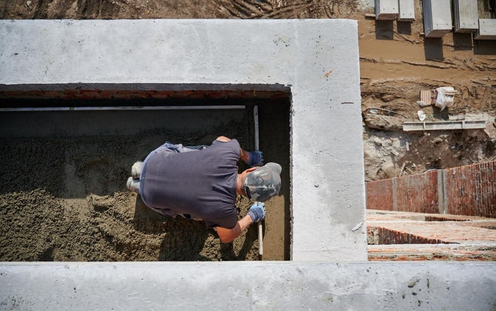 Construction worker leveling sand in a concrete foundation