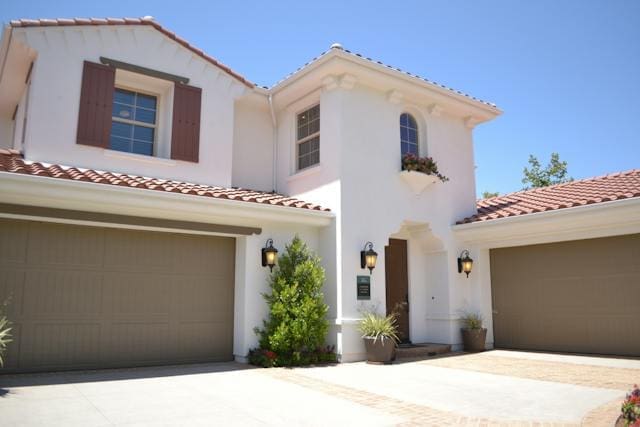 White stucco house with terracotta roof, two garages, and landscaping