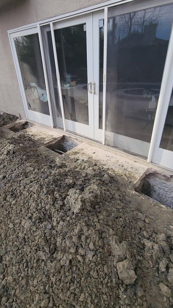 Dirt piled up against a house with sliding glass doors