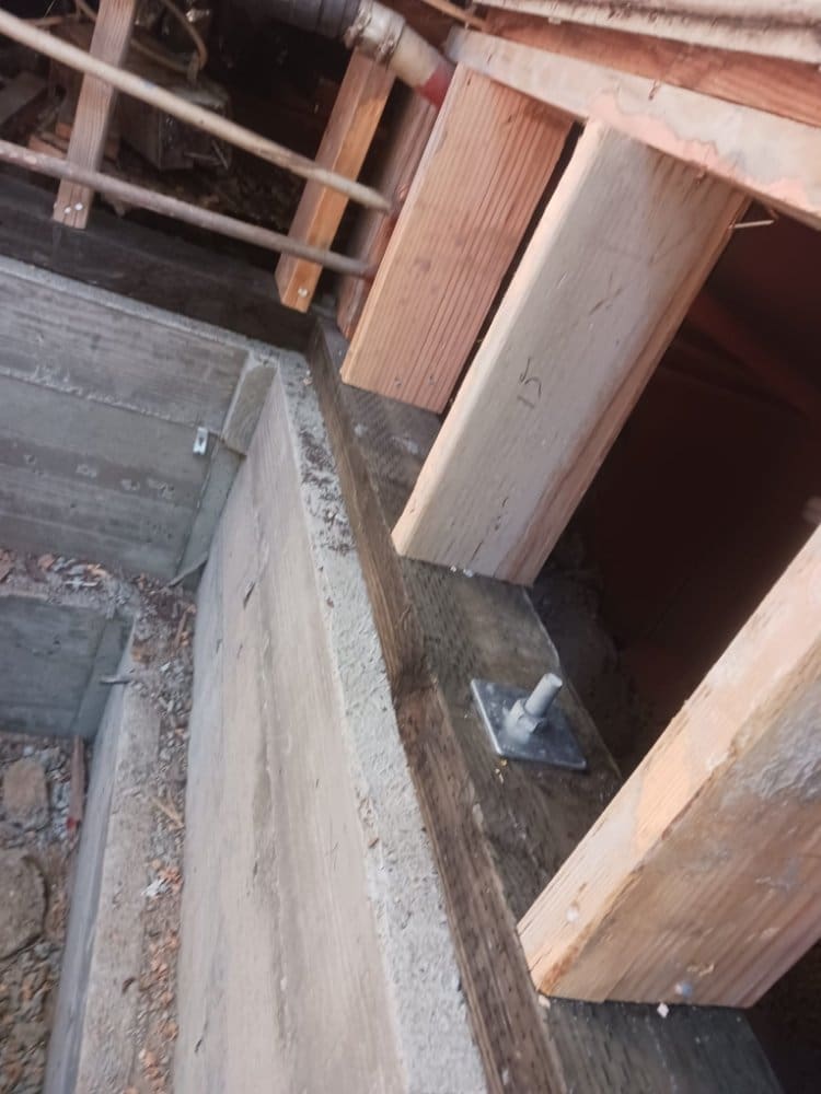 Concrete foundation with wooden beams and metal anchor bolts visible