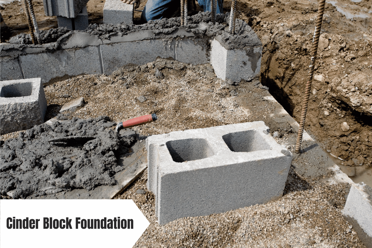 Cinder block foundation being constructed with rebar and wet cement.