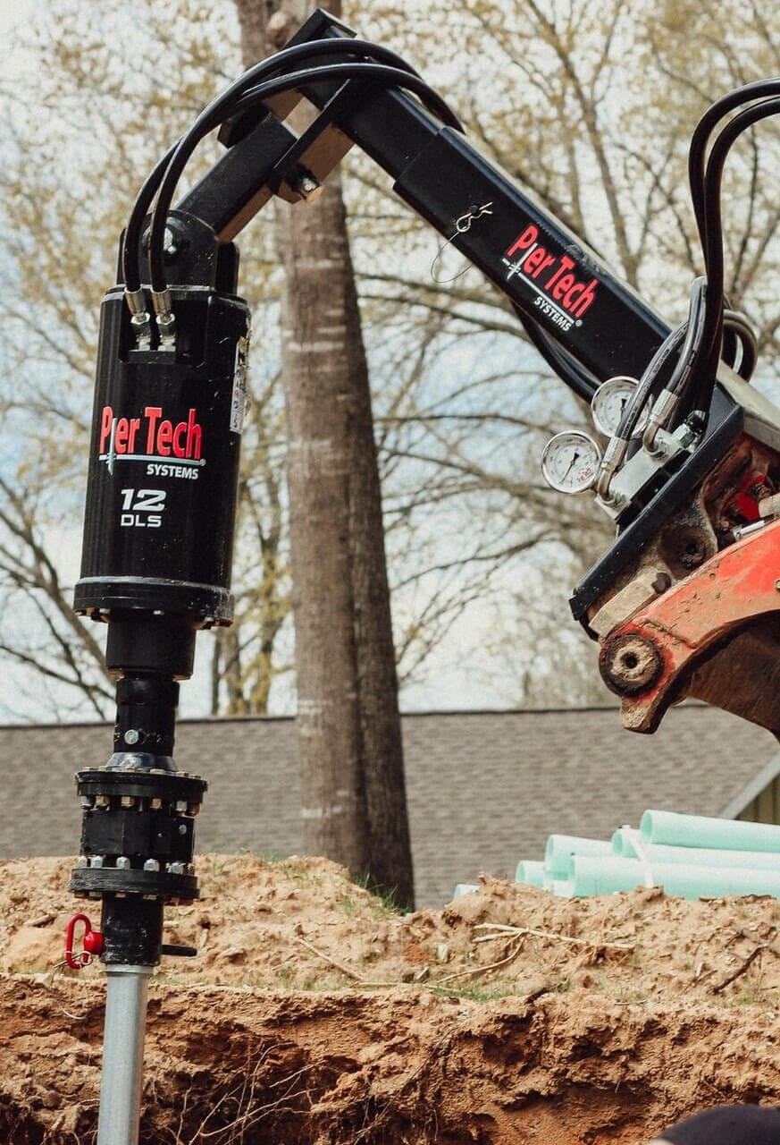 Heavy machinery installing a foundation pier into the ground